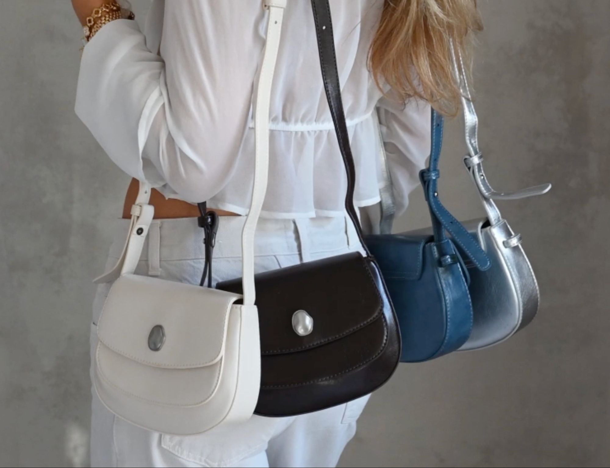 Person holding multiple handbags against a neutral background