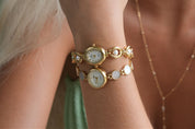 Gold watch and bracelet set on a wrist with a blurred background