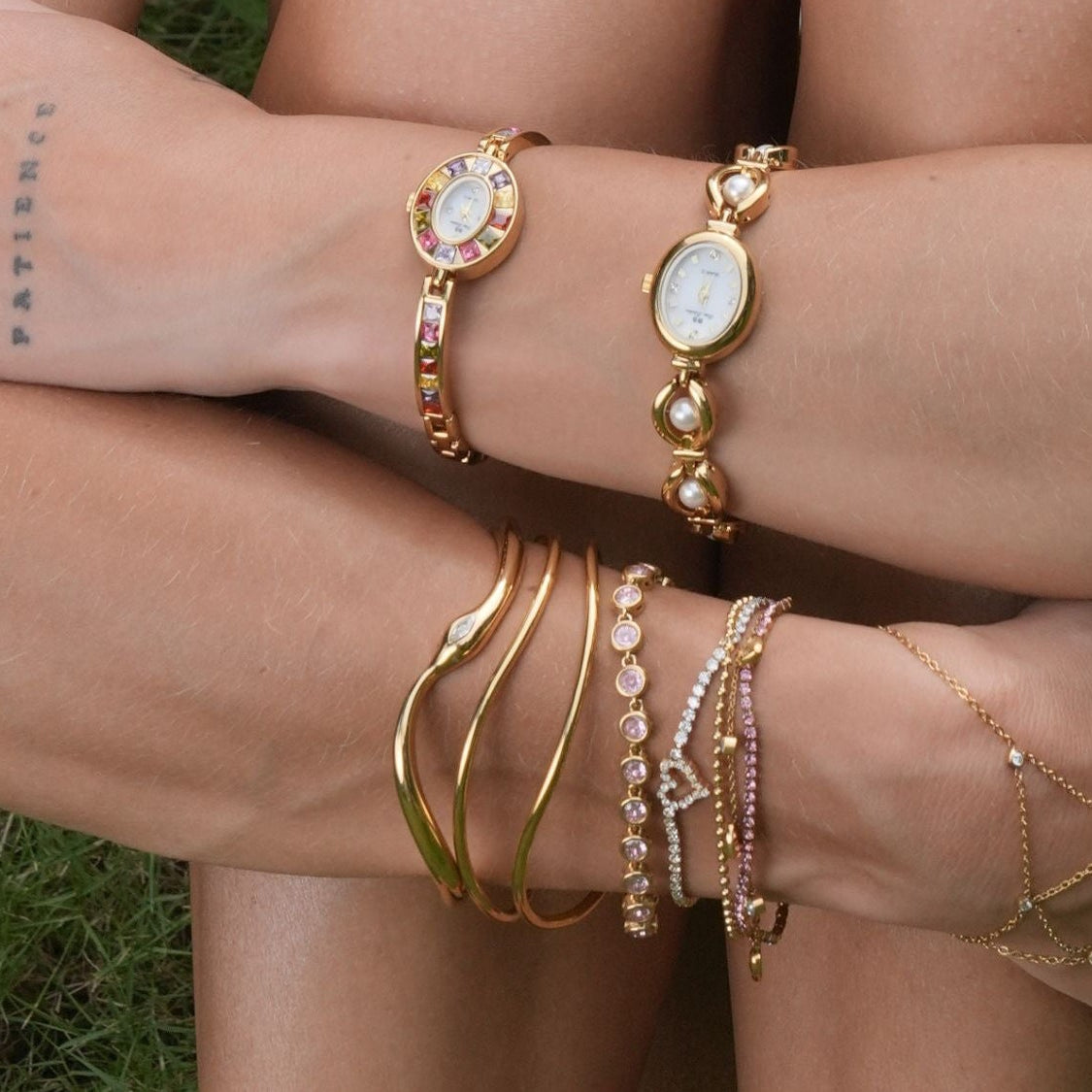 Persona con diversi braccialetti d'oro su uno sfondo erboso