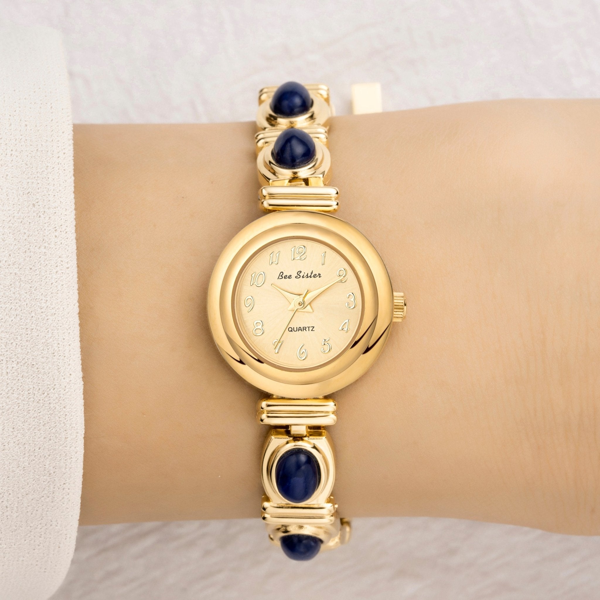 Montre-bracelet en or avec pierres précieuses bleues au poignet sur fond neutre