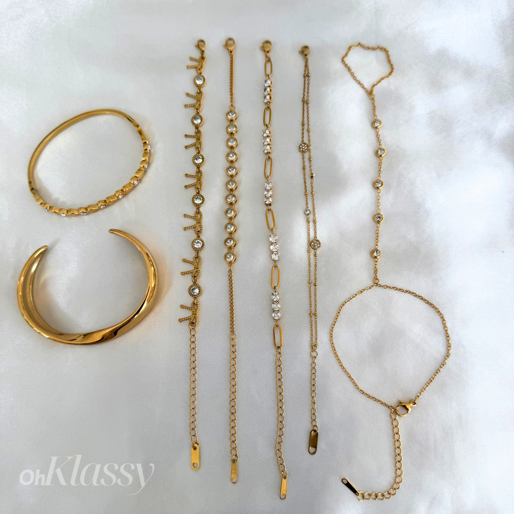 Set of gold jewelry including bracelets and a ring on a white background with 'oh Klassy' branding.