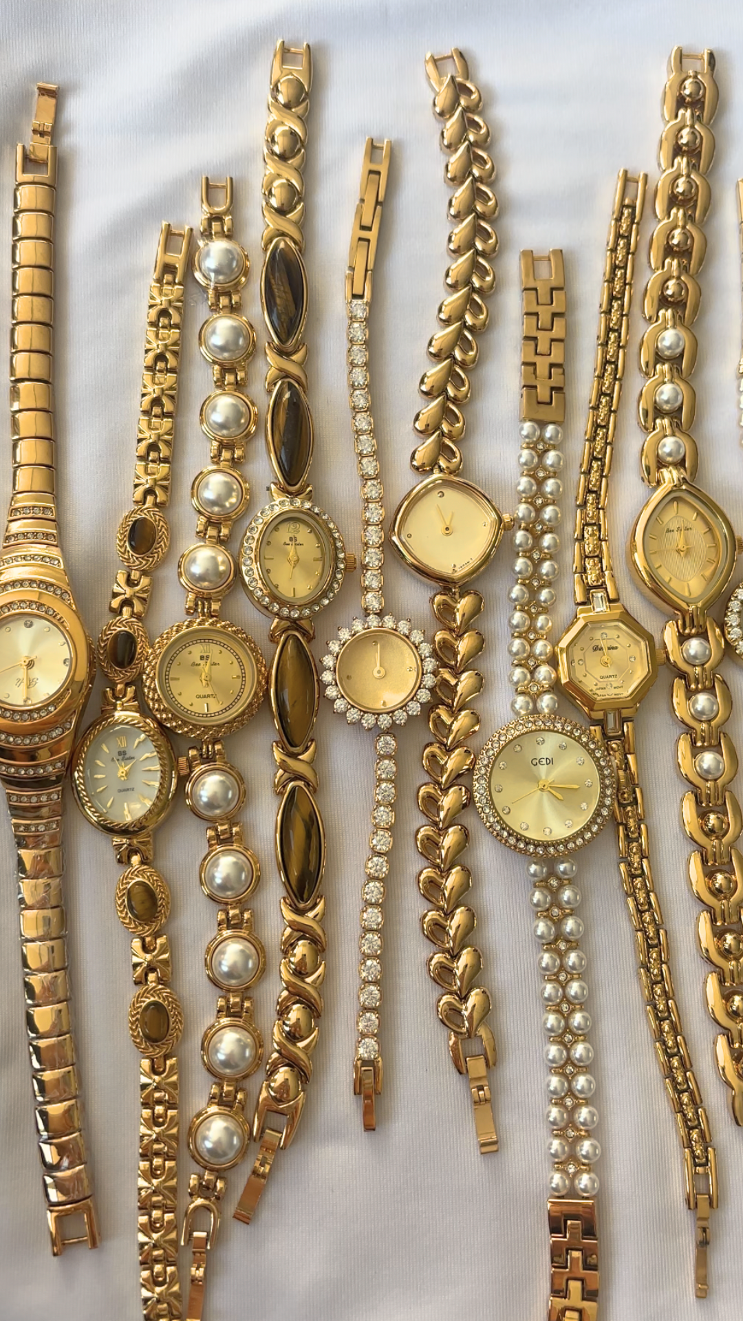 Collezione di orologi da polso e bracciali in oro su sfondo bianco