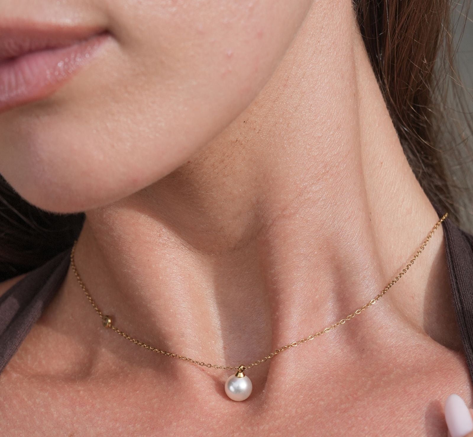 Close-up van een vrouw die pareloorbellen en een ketting draagt.